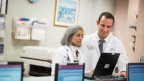 Two physicians look at a computer in the hospital.