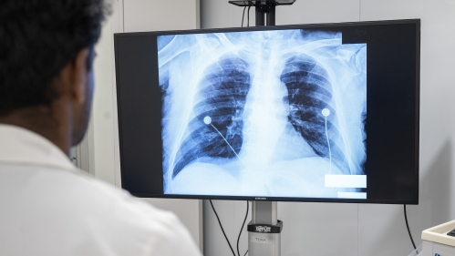 Medical students check vital sign monitors and x-rays in a sim lab