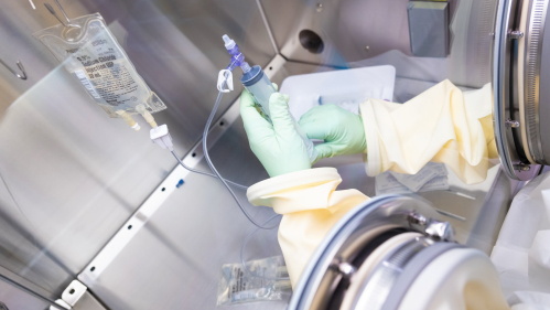 A person prepares medication in a sterile chamber in the clinical research center