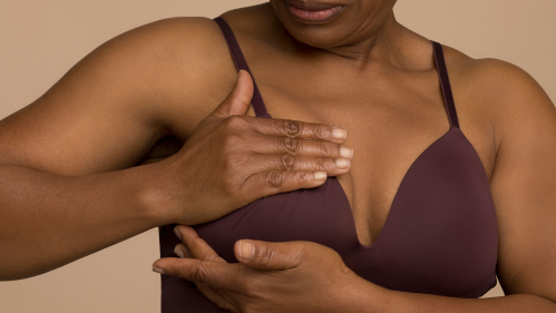 woman examines her breast for cancer