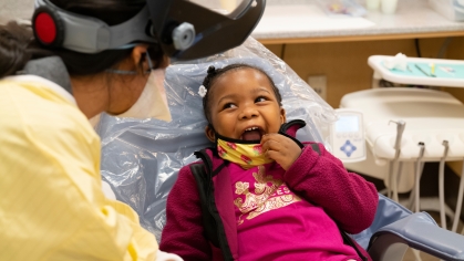 A child sits in an exam chair at the school of dental medicine's pediatric clinic