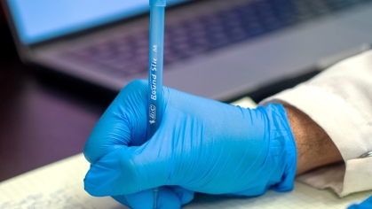 A researcher writes notes in a book