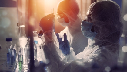 Researchers work in a lab while wearing gloves and masks