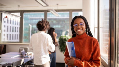 A student wearing a red sweater works at a laptop