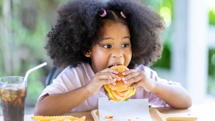 Black girl eating a burger and fries