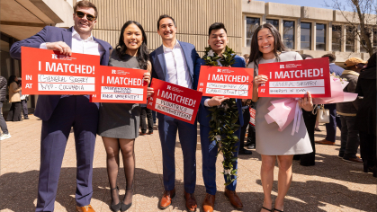 Students holding signs that say where they matched 