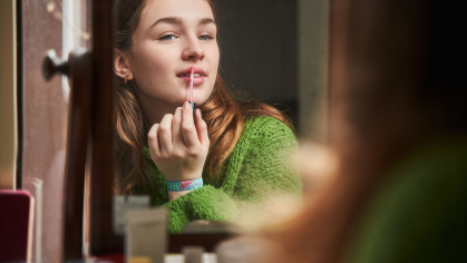 teen girl applies lip gloss