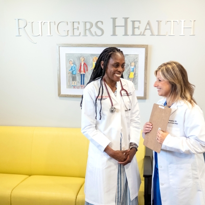 Two doctors in white coats talk in a Rutgers Health office