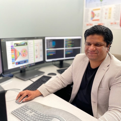 A researcher works at a desk surrounded by computer monitors