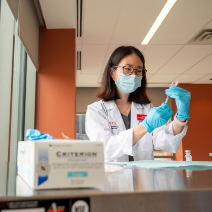 A pharmacy student draws medication into a syringe