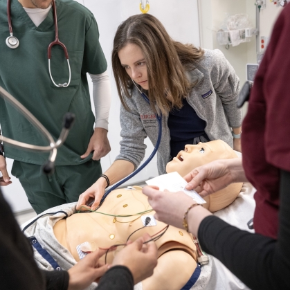 Medical students practice a patient examination on a manikin in a simulation lab