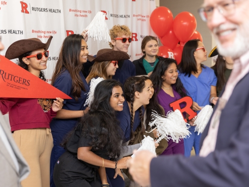 Students pose with funny hats and pompoms for a photo at the 10th anniversary celebration