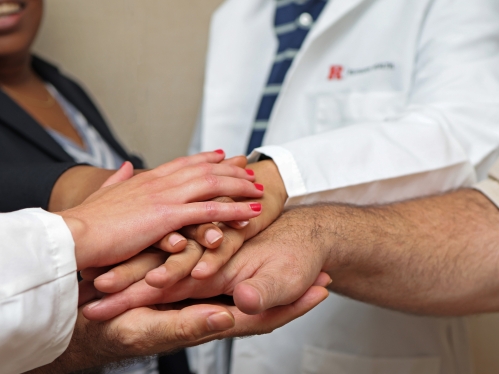 People stack their hands to signify teamwork and collaboration or community