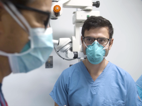 A medical resident looks on while a faculty member gives instructions