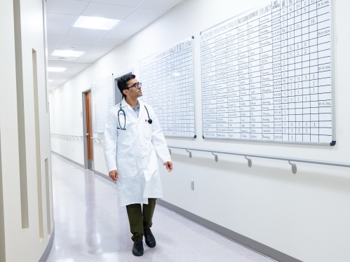 A clinician walks down the hall past dry erase boards with clinical trial schedules in the clinical research center at Rutgers.