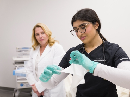 A nursing student practices clinical skills while an instructor watches