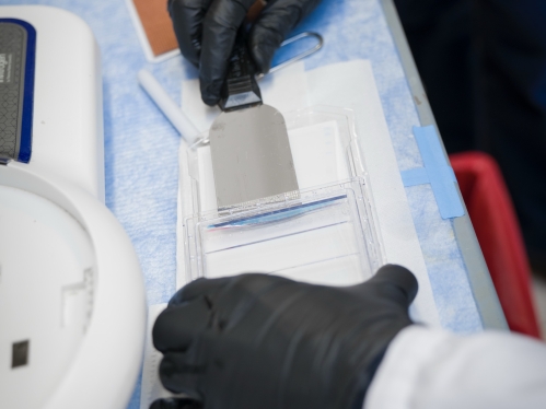 A researcher wearing gloves uses instruments in a lab at Rutgers