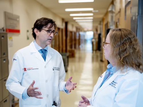 Researchers Christian Hinrichs and Eileen White talk in a hallway at Rutgers Cancer Institute.