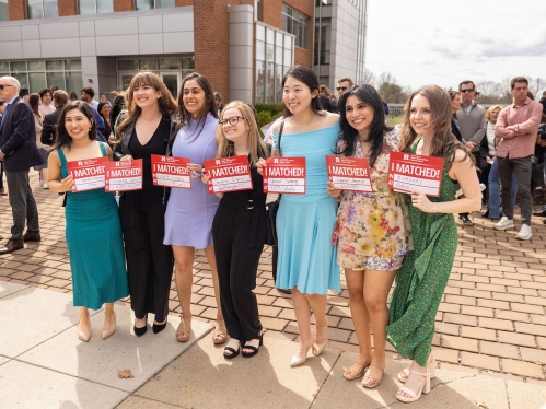 Women Med Students holding up signs that say where they matched 