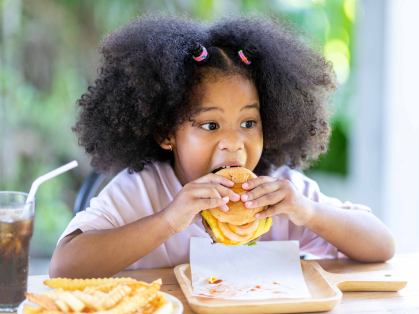 Black girl eating a burger and fries