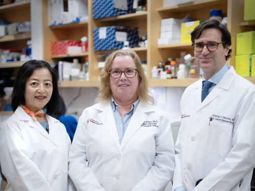 Three Rutgers Cancer Institute researchers wearing white coats standing in a lab.