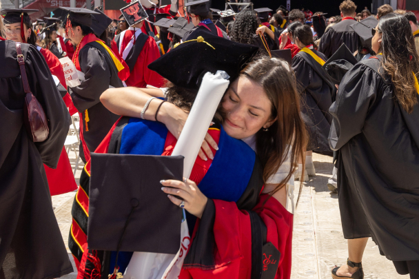 Two graduates hugging each other at commencement
