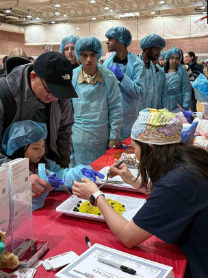 A child performs surgery on a Jell-O brain at the Health Village on Busch campus.