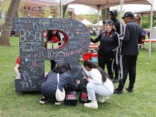 Visitors decorate a large three-dimensional "R" on Voorhees Mall during Rutgers Day 2024.