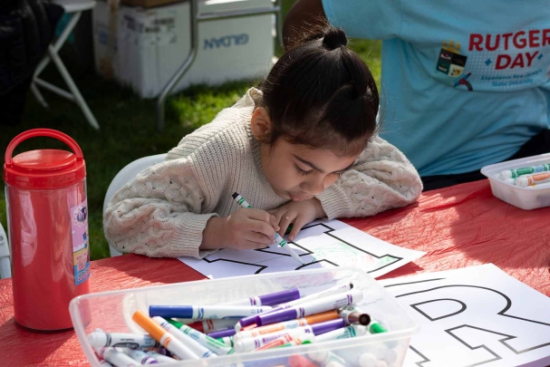 Luciana Medina colors a Rutgers “R” at the R Garden on Voorhees Mall during Rutgers Day 2024.